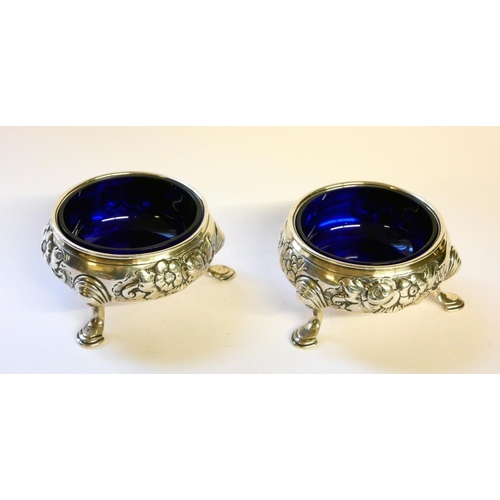 444 - A PAIR OF GEORGE II SILVER AND BLUE GLASS SALTS
Having embossed decoration and tripod legs, hallmark... 