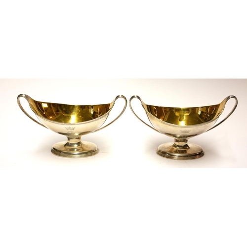 448 - A PAIR OF GEORGIAN SILVER NAVETTE FORM SALTS
With twin handles and gilt interior and engraved crest ... 