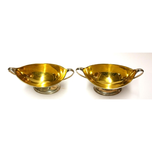 448 - A PAIR OF GEORGIAN SILVER NAVETTE FORM SALTS
With twin handles and gilt interior and engraved crest ... 