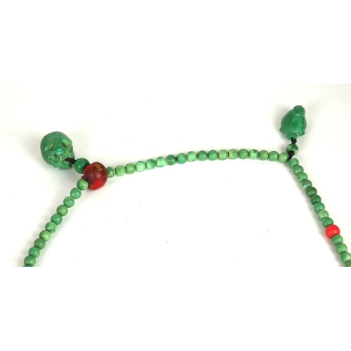 302A - A CHINESE CARVED JADEITE AND CORAL NECKLACE
The single strand of spherical beads with carved skulls ... 