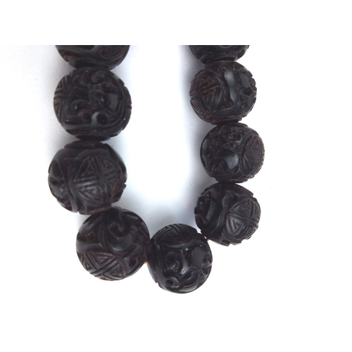 129a - A CHINESE CARVED WOODEN BEAD NECKLACE
The single strand of ebonised beads. 
(approx 65cm)
