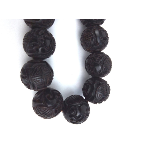 129a - A CHINESE CARVED WOODEN BEAD NECKLACE
The single strand of ebonised beads. 
(approx 65cm)