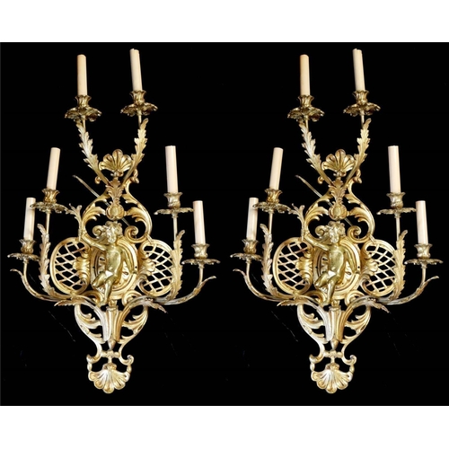 682 - A LARGE PAIR OF EARLY 20TH CENTURY POLISHED BRASS SIX BRANCH WALL SCONCES
With drip trays above acan... 