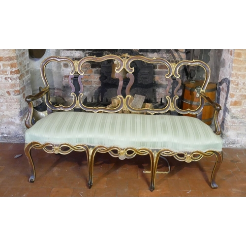 687 - AN 18TH CENTURY ITALIAN WALNUT AND PARCEL GILT OPEN ARM CHAIR SETTEE
With pierced strap work back an... 