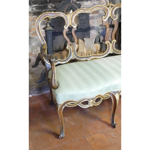 687 - AN 18TH CENTURY ITALIAN WALNUT AND PARCEL GILT OPEN ARM CHAIR SETTEE
With pierced strap work back an... 