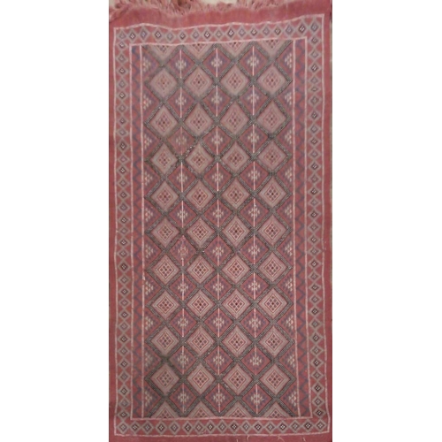 696 - A TUNISIAN MERGOUM WOOLLEN RUG
With geometric and abstract patterns to central field on red ground w... 