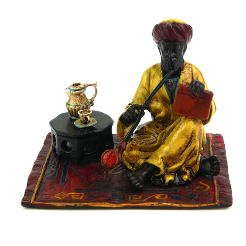 484 - A COLD PAINTED BRONZE FIGURE OF AN ARAB
Seated pose with hooker pipe and Persian design carpet. 
(ap... 