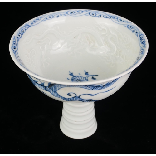 524 - A 20TH CENTURY CHINESE DESIGN BLUE AND WHITE PORCELAIN STEM CUP
Interior moulded with a dragon chasi... 