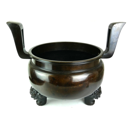 543 - A VERY LARGE ORIENTAL BRONZE CENSER 
Having two archaic shaped handles, supported by three temple li... 