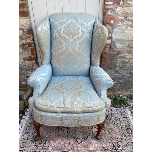 792 - AN EARLY 20TH CENTURY WING ARMCHAIR
Fashioned in the Georgian style, in blue floral fabric upholster... 