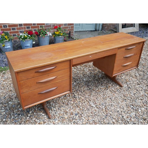 776 - AUSTINSUITE, A MID CENTURY TEAK DESK/DRESSING TABLE 
Designed by Frank Guille, with two banks of thr... 