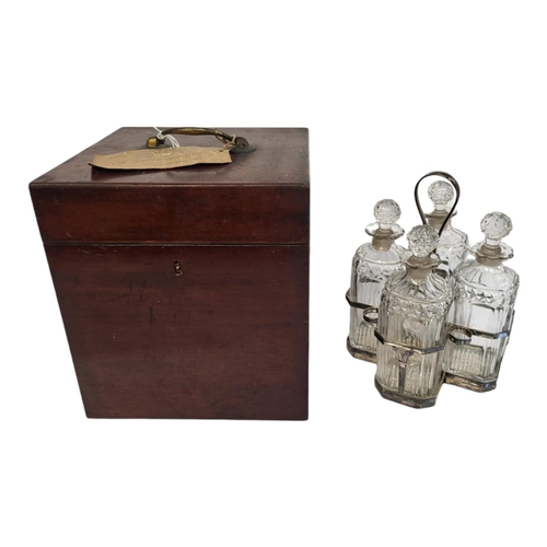 39 - A GEORGIAN SILVER AND CUT GLASS FOUR BOTTLE DECANTER SET
Having a reeded handle, on classical urn fo... 