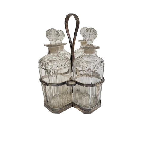 39 - A GEORGIAN SILVER AND CUT GLASS FOUR BOTTLE DECANTER SET
Having a reeded handle, on classical urn fo... 