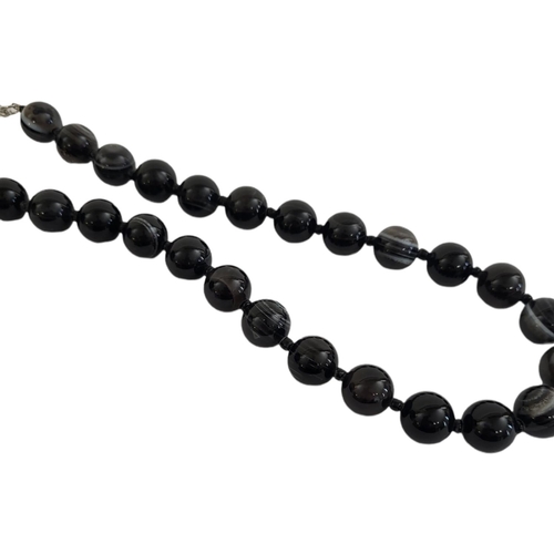 54 - A BULLSEYE AGATE NECKLACE 
Consisting of twenty-nine solid spherical agates on a white metal clasp.
... 