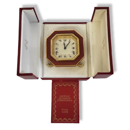 46 - CARTIER, MUST DE CARTIER, A VINTAGE GILT METAL AND ENAMEL TRAVEL CLOCK
Octagonal form with red ename... 