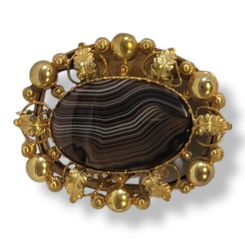 1a - A 19TH CENTURY YELLOW METAL AND AGATE BROOCH
Central oval cut stone in a wide scrolled and pierced y... 