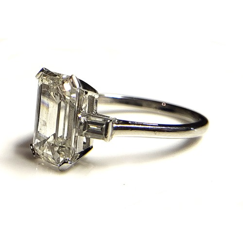 267 - AN 18CT WHITE GOLD AND 4.37CT DIAMOND SOLITAIRE RING
The faceted emerald cut stone flanked by baguet... 