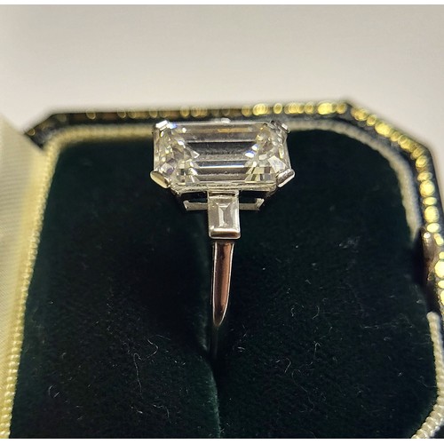 267 - AN 18CT WHITE GOLD AND 4.37CT DIAMOND SOLITAIRE RING
The faceted emerald cut stone flanked by baguet... 