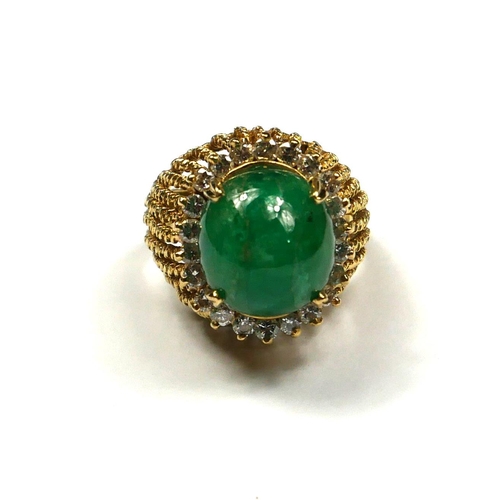 239 - AN 18CT GOLD, EMERALD AND DIAMOND RING
The cabochon cut emerald edged with round cut diamonds in a p... 