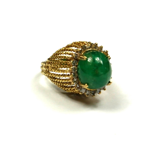 239 - AN 18CT GOLD, EMERALD AND DIAMOND RING
The cabochon cut emerald edged with round cut diamonds in a p... 