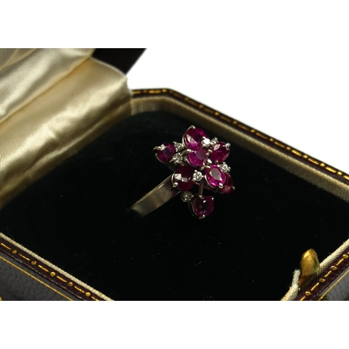 246 - A PLATINUM, RUBY AND DIAMOND CLUSTER RING
The arrangement of graduated round cut rubies interspersed... 