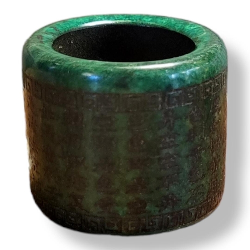 318A - A 20TH CENTURY GREEN GLAZED JADE ARCHERS RING
Bearing Chinese inscription. 
(h 3cm)