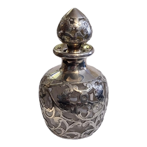 116 - A CONTINENTAL SILVER AND GLASS SCENT BOTTLE
Having pierced and scrolled overlaid silver decoration a... 