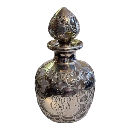 116 - A CONTINENTAL SILVER AND GLASS SCENT BOTTLE
Having pierced and scrolled overlaid silver decoration a... 