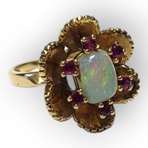 65 - A VINTAGE 18CT GOLD, OPAL AND RUBY RING
The central cabochon cut oval opal edged with round cut rubi... 