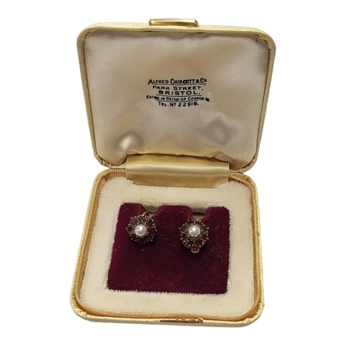 73 - A PAIR OF 9CT GOLD, GARNET AND PEARL EARRINGS
The single pearl edged with garnets forming a daisy cl... 