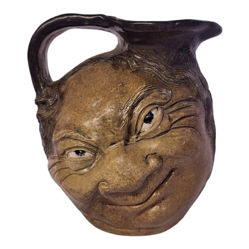 247 - AN EARLY 20TH CENTURY MARTIN BROTHERS STYLE STONEWARE EWER
Moulded with grotesque smiling figure, se... 