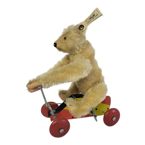 261 - STEIFF, A VINTAGE CLOCKWORK TEDDY BEAR
Seated pose on metal clockwork trolley, retaining Steiff tag ... 