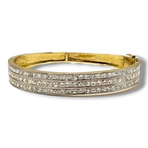 21B - A YELLOW METAL AND DIAMOND BANGLE
Set with three rows of princess cut diamonds.
(approx total diamon... 