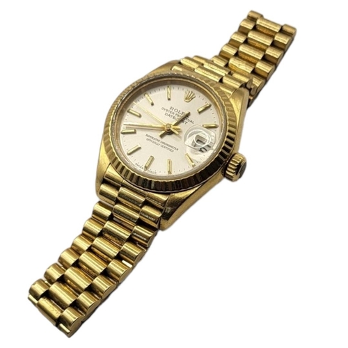 28B - ROLEX, DATEJUST, A VINTAGE 18CT GOLD LADIES’ WRISTWATCH
Having a silver tone dial with calendar wind... 