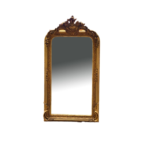 609 - A REGENCY STYLE GILT FRAMED OVERMANTLE MIRROR
Crested with a foliage cartouche above an arched bevel... 
