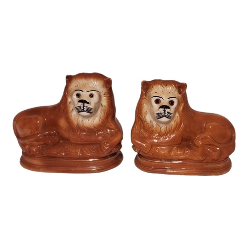 191 - A PAIR OF 19TH CENTURY STAFFORDSHIRE POTTERY LIONS
Recumbent pose with glass eyes, small air hole to... 