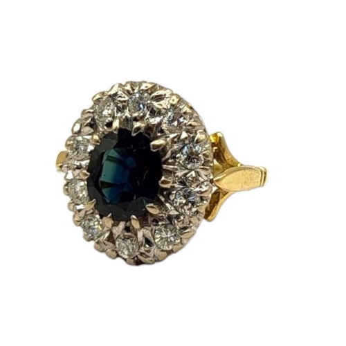 64 - AN 18CT GOLD, SAPPHIRE AND DIAMOND CLUSTER RING
The central oval cut sapphire edged with round cut d... 