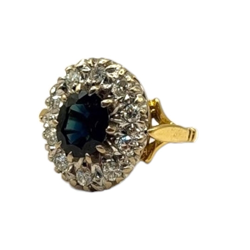 64 - AN 18CT GOLD, SAPPHIRE AND DIAMOND CLUSTER RING
The central oval cut sapphire edged with round cut d... 