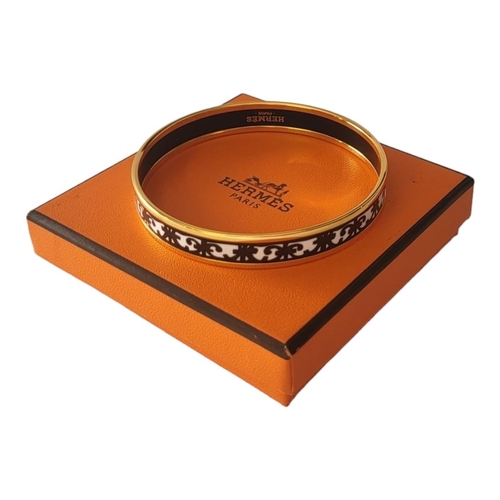 28 - HERMÈS, A VINTAGE GOLD PLATE AND ENAMEL BANGLE
Having a fleur-des-lis design, marked ‘Hermès, Paris’... 