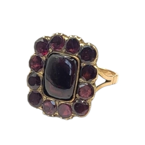 35 - A 19TH CENTURY YELLOW METAL AND GARNET RING
The central oval cut garnet with round cut stones to out... 