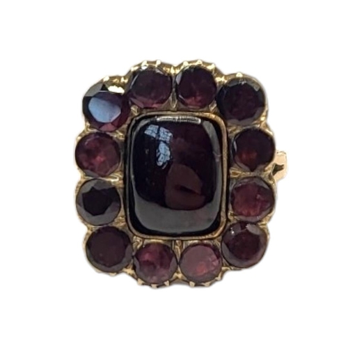 35 - A 19TH CENTURY YELLOW METAL AND GARNET RING
The central oval cut garnet with round cut stones to out... 