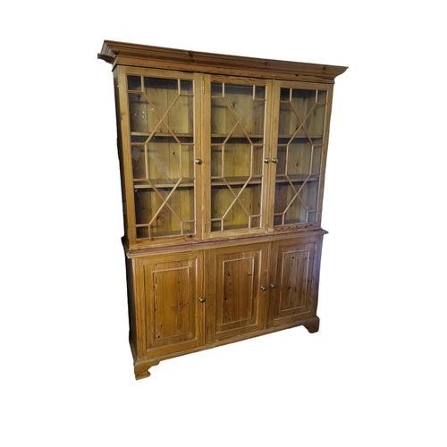 585 - A 19TH CENTURY STYLE PINE TRIPLE BOOKCASE
With three astragal glazed doors above panelled cupboards.... 