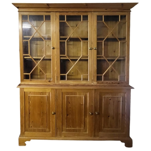 585 - A 19TH CENTURY STYLE PINE TRIPLE BOOKCASE
With three astragal glazed doors above panelled cupboards.... 