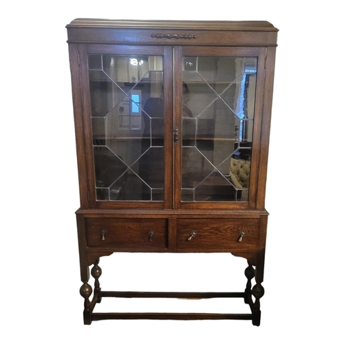 591A - AN EARLY 20TH CENTURY OAK BOOKCASE ON STAND
With two glazed doors above drawers and under tier.
(110... 