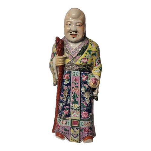 447 - A CHINESE QING DYNASTY FAMILLE ROSE PORCELAIN FIGURE OF AN IMMORTAL 
Dressed in a flowing robe in po... 