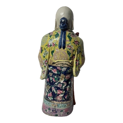 447 - A CHINESE QING DYNASTY FAMILLE ROSE PORCELAIN FIGURE OF AN IMMORTAL 
Dressed in a flowing robe in po... 