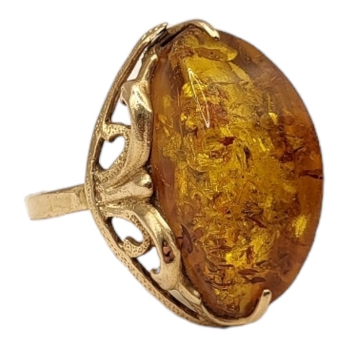 28A - A VINTAGE 14CT GOLD AND AMBER RING
The cabochon cut stone set in a pierced design.
(size N)

Conditi... 