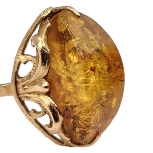 28A - A VINTAGE 14CT GOLD AND AMBER RING
The cabochon cut stone set in a pierced design.
(size N)

Conditi... 