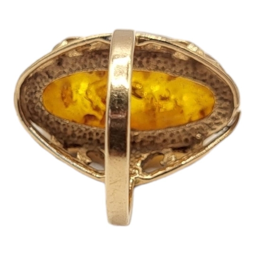 28A - A VINTAGE 14CT GOLD AND AMBER RING
The cabochon cut stone set in a pierced design.
(size N)

Conditi... 