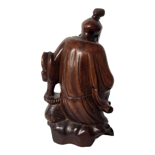 393 - AN EARLY 20TH CENTURY CHINESE HARDWOOD CARVING, A SEATED SCHOLAR WEARING A LONG ROBE
On a rustic roc... 